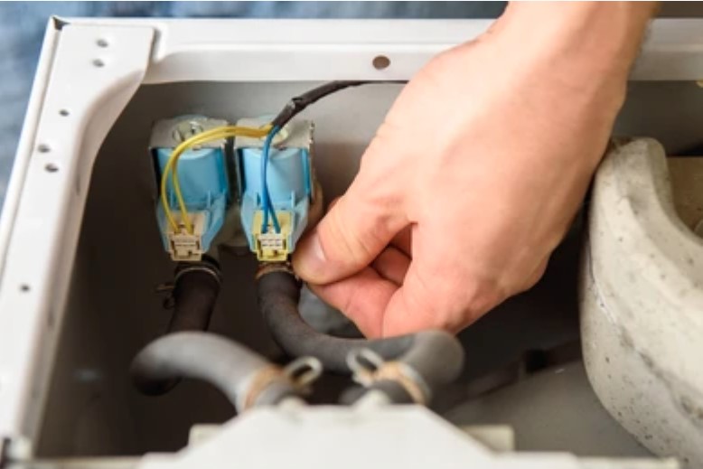 a man is fixing a washing machine checks water inlet valve