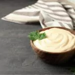 bowl with mayonnaise parsley and towel on dark background