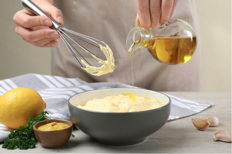 woman making homemade mayonnaise sauce with olive oil