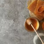 composition with honeycombs honey and jars on a grey background