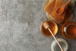composition with honeycombs honey and jars on a grey background