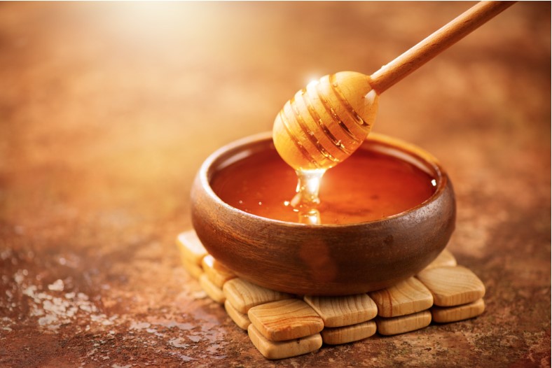 healthy organic thick honey dipping from the wooden honey spoon