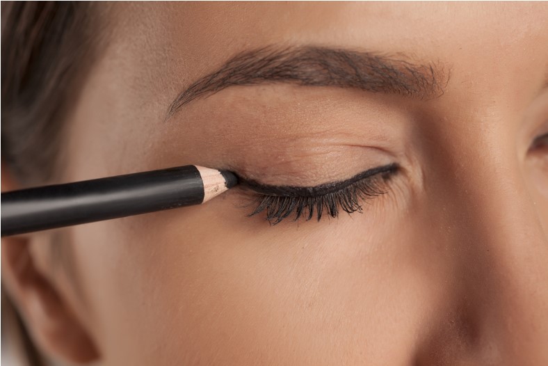 young woman applying eyeliner