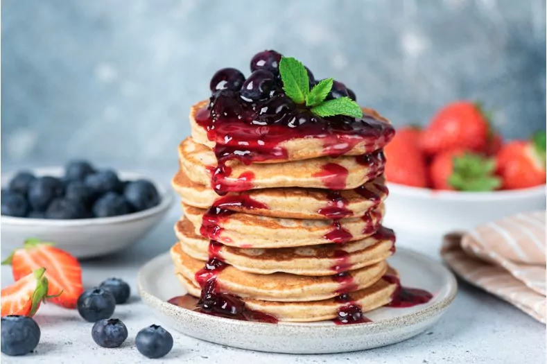 delicious oatmeal pancakes with berry fruit blueberry strawberry jam dessert topping blue background