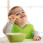 happy infant baby boy spoon eats itself