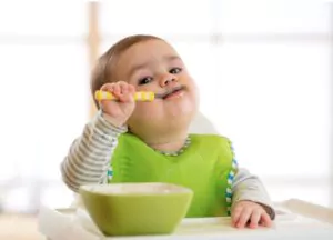 happy infant baby boy spoon eats itself