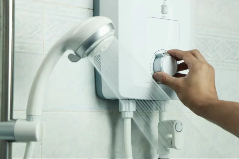 hands regulating the temperature of hot water in electric water heater