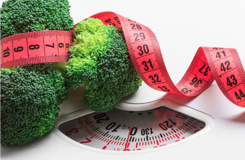 closeup green broccoli with measuring tape on white scales