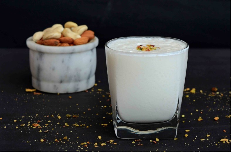 a glass of sweet dry fruit lassi on a background
