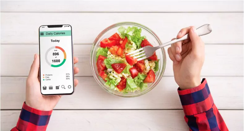 man eating vegetable salad and counting calories on mobile application