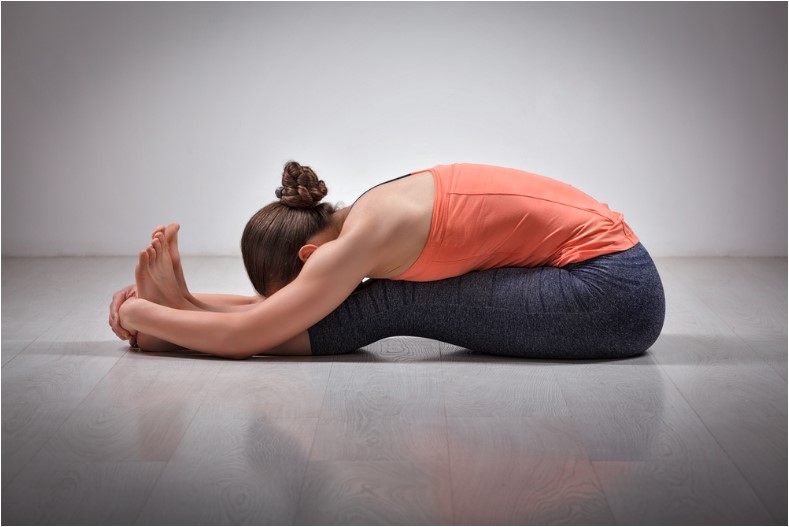 sporty fit woman practices ashtanga vinyasa yoga back bending asana paschimottanasana seated forward bend