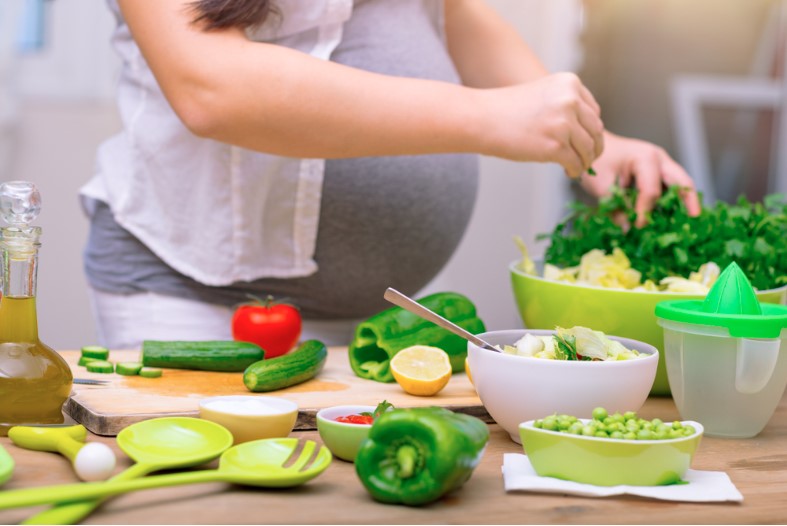 happy pregnant woman cooking at home