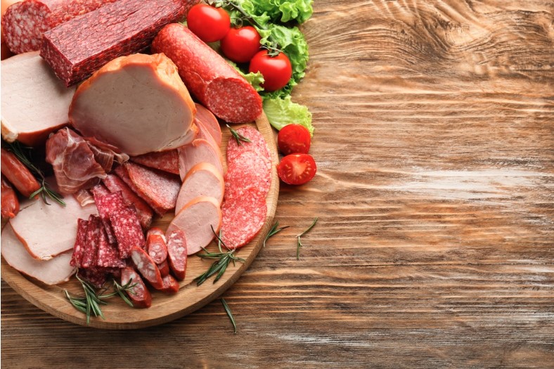 assortment of delicious deli meats on wooden board