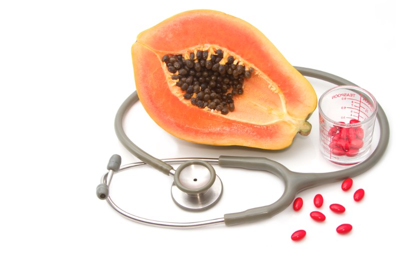 pill and stethoscope with papaya fruit vitamin supplement and nutrition concept