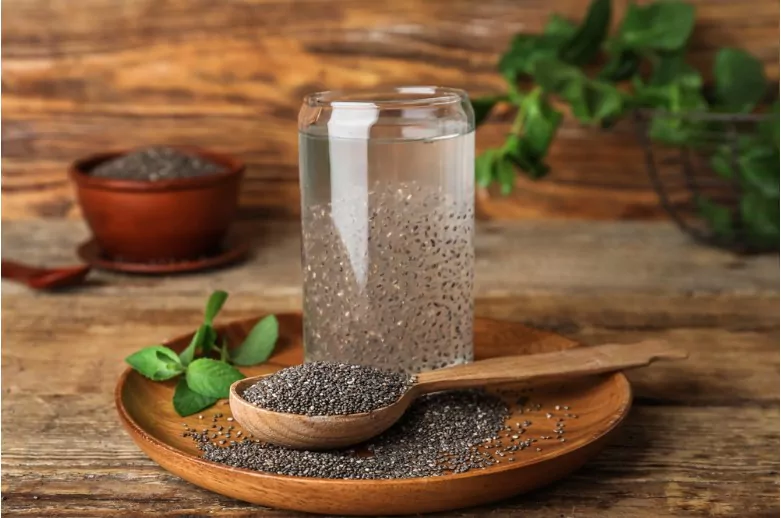 glass with drink and chia seeds on wooden background