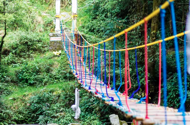 a hanging rope bridge over the waterfall in panchpula dalhousie