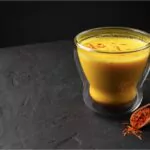 saffron latte in a glass cup on a black concrete background