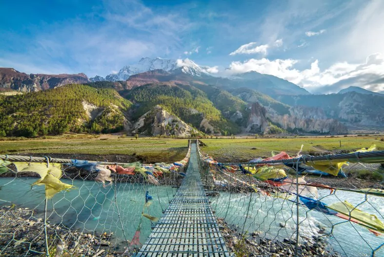suspension bridge with buddhist prayer flags on the annapurna circuit trek in nepal