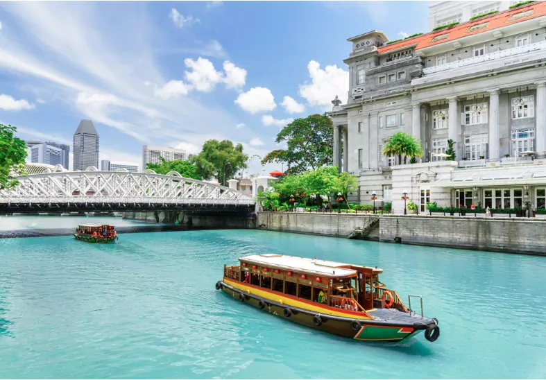 beautiful view of traditional tourist boats sailing along the singapore river with azure water in downtown of singapore