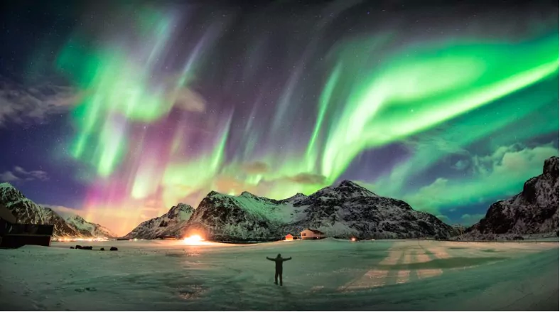 northern lights over mountain with one person at skagsanden beach