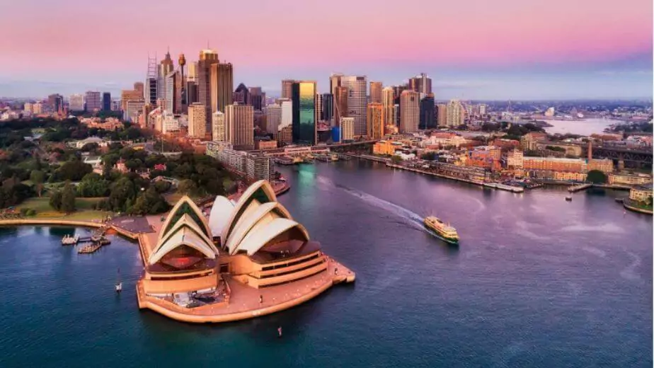 pinkish colourful sunrise over sydney city cbd on waterfront of harbour around circular quay with major architectural landmarks and symbols of australia