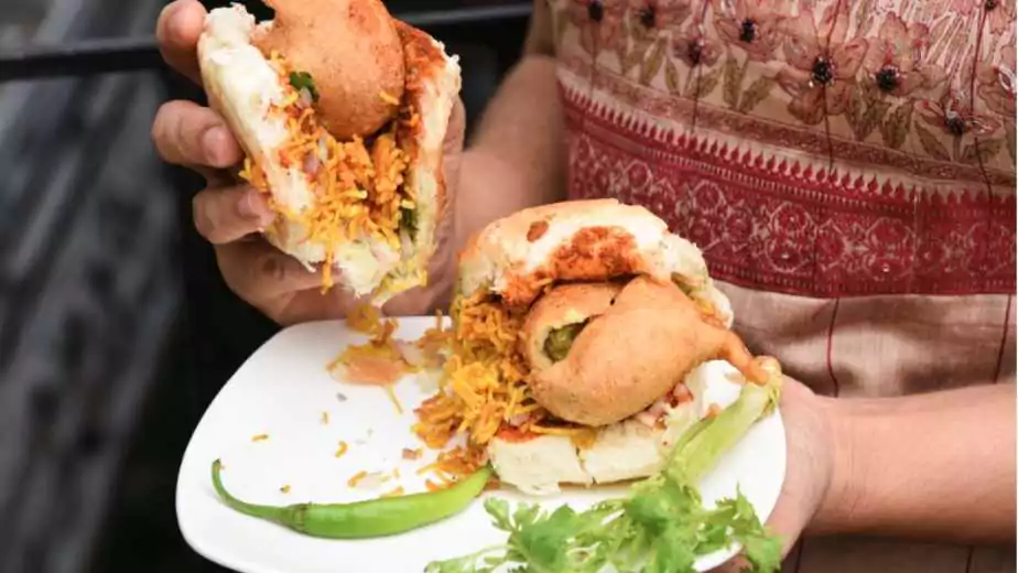 a woman eating vada pav street food in mumbai