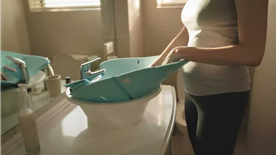 young mom placing baby bath seat into bathroom sink at home
